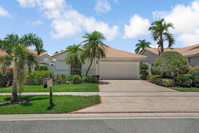 9703 Harbour Lake Cir, Boynton Beach, FL 33437 - mediterranean / spanish-style home featuring an attached garage, concrete driveway, a tile roof, stucco siding, and a front yard