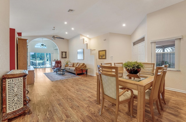 dining room with arched walkways, vaulted ceiling, baseboards, visible vents, and light wood-style floors