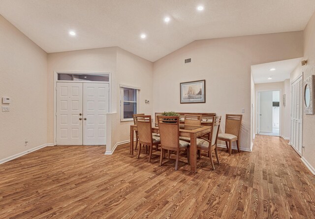 dining room with recessed lighting, lofted ceiling, wood finished floors, visible vents, and baseboards