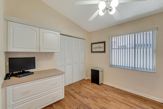 unfurnished office with light wood-type flooring, vaulted ceiling, baseboards, and a ceiling fan