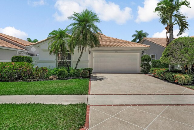 9703 Harbour Lake Cir, Boynton Beach, FL 33437 - mediterranean / spanish home featuring an attached garage, stucco siding, a tiled roof, concrete driveway, and a front lawn