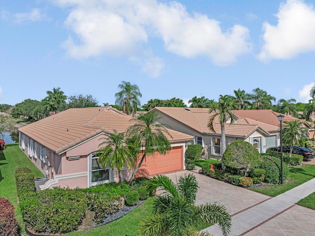 exterior space with a tiled roof, concrete driveway, an attached garage, stucco siding, and a front yard