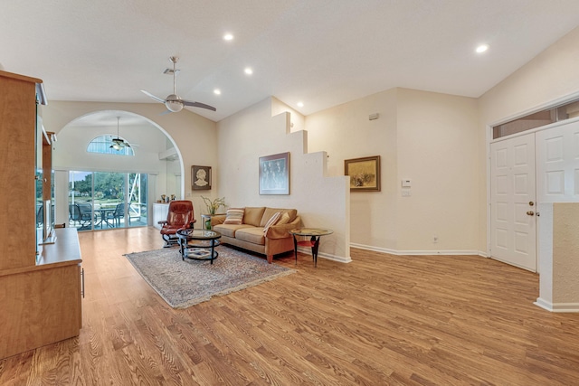 living area with light wood-type flooring, a ceiling fan, baseboards, and arched walkways