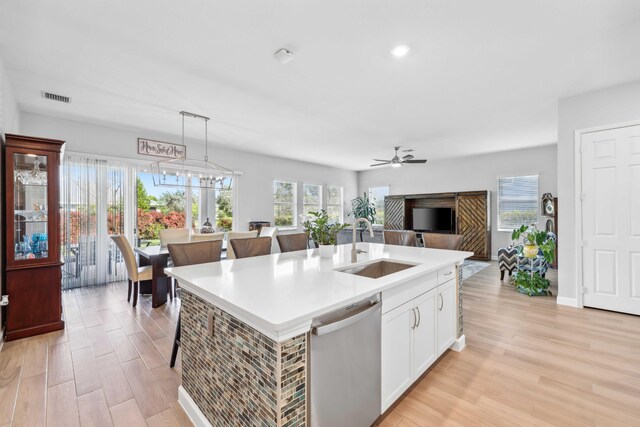 1104 Wandering Willow Way, Loxahatchee, FL 33470 - kitchen featuring stainless steel dishwasher, visible vents, a center island with sink, light wood-type flooring, and a sink