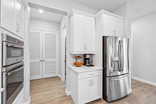 1104 Wandering Willow Way, Loxahatchee, FL 33470 - kitchen with light countertops, baseboards, white cabinets, light wood-style floors, and stainless steel appliances