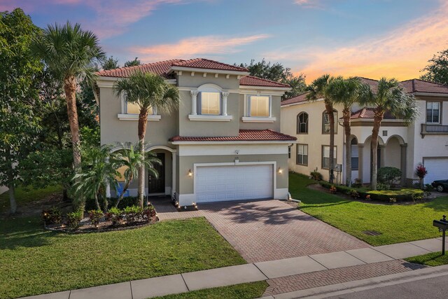 1070 Grove Park Cir, Boynton Beach, FL 33436 - mediterranean / spanish house with decorative driveway, a front lawn, a tiled roof, an attached garage, and stucco siding