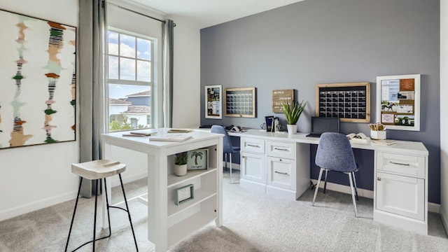 home office featuring light colored carpet, built in study area, and baseboards
