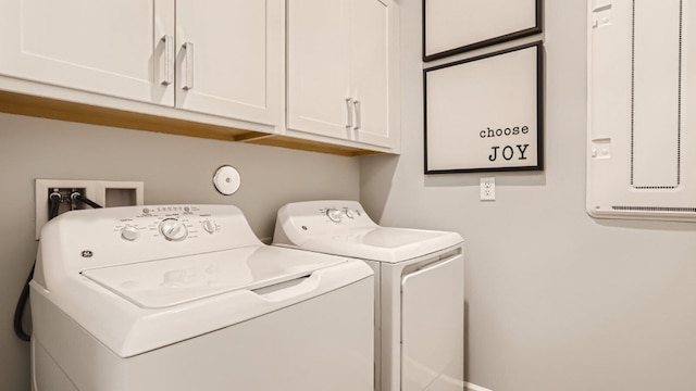 clothes washing area with separate washer and dryer and cabinet space