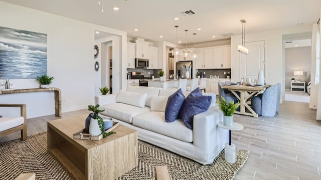 living area featuring visible vents, baseboards, light wood-type flooring, and recessed lighting