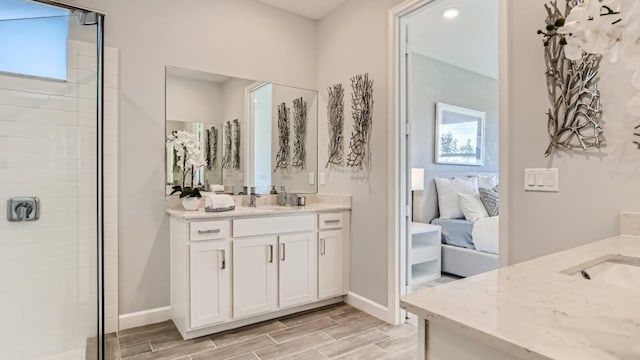 ensuite bathroom featuring a wealth of natural light, two vanities, and wood finish floors