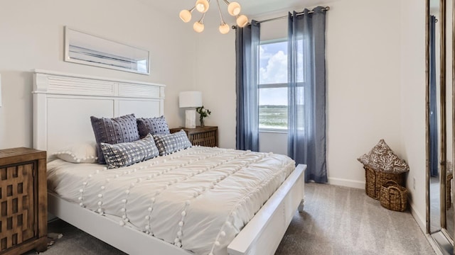 carpeted bedroom featuring a water view, baseboards, and a chandelier