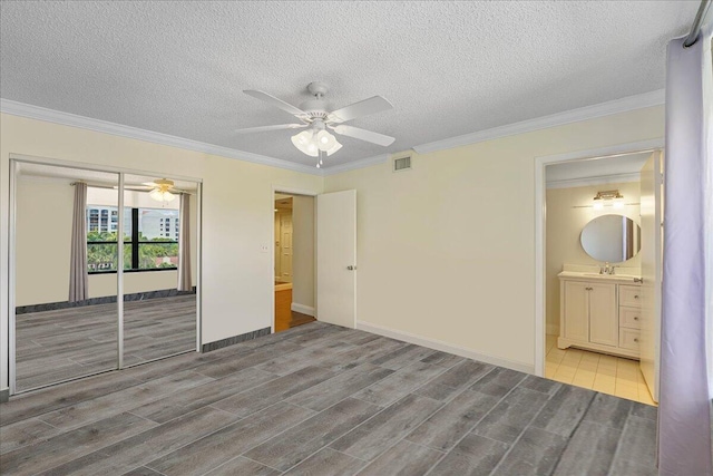 7572 Regency Lake Dr Unit 501, Boca Raton, FL 33433 - unfurnished bedroom featuring wood finished floors, a sink, crown molding, a closet, and a textured ceiling