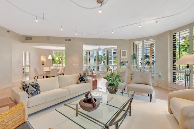 living area with track lighting, tile patterned floors, visible vents, and baseboards