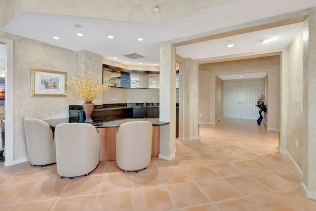 corridor with light tile patterned floors, baseboards, recessed lighting, and a sink