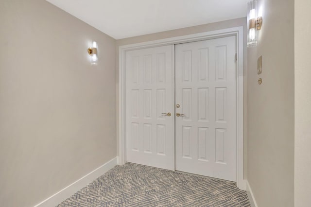 doorway with baseboards and dark carpet