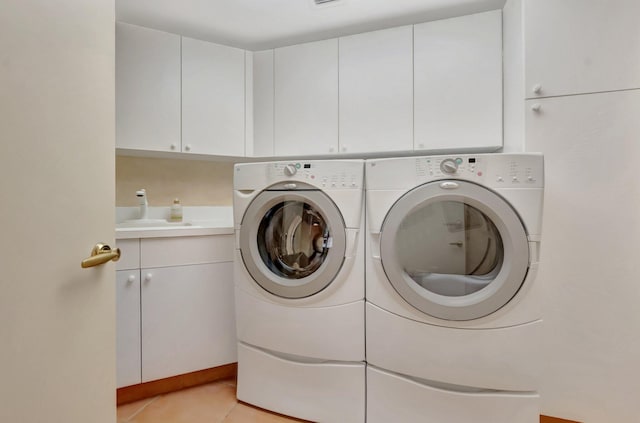 clothes washing area with washing machine and clothes dryer, cabinet space, light tile patterned floors, and a sink
