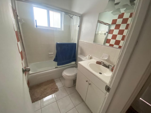 bathroom featuring toilet, tile walls, tile patterned flooring, vanity, and enclosed tub / shower combo