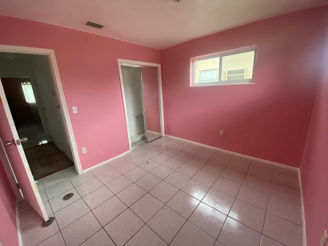 unfurnished bedroom with baseboards, light tile patterned flooring, visible vents, and a closet