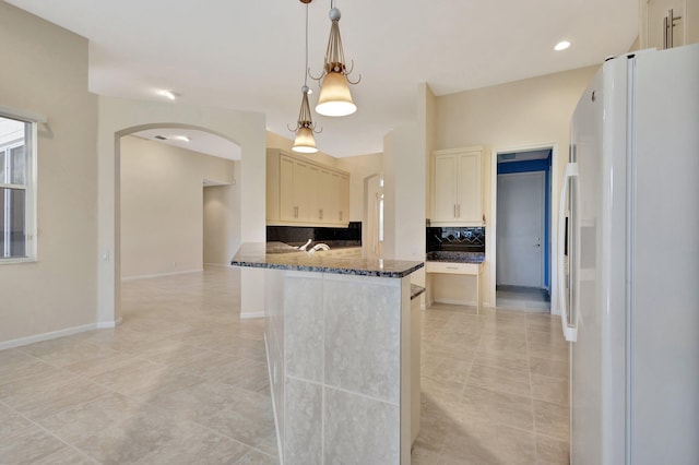 5266 Landon Cir, Boynton Beach, FL 33437 - kitchen with dark stone countertops, freestanding refrigerator, backsplash, decorative light fixtures, and arched walkways