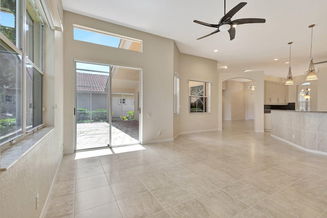 5266 Landon Cir, Boynton Beach, FL 33437 - unfurnished living room featuring arched walkways, ceiling fan, light tile patterned flooring, and a healthy amount of sunlight