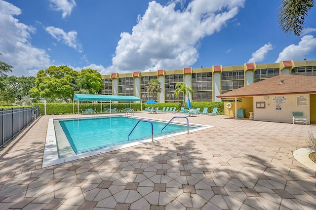 community pool with a patio area and fence