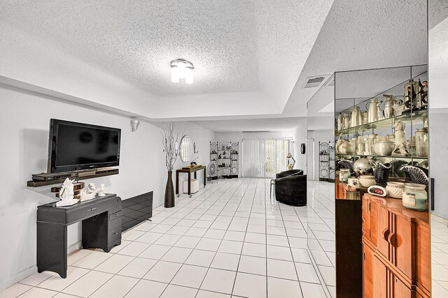 living area featuring a raised ceiling, a textured ceiling, light tile patterned floors, and visible vents
