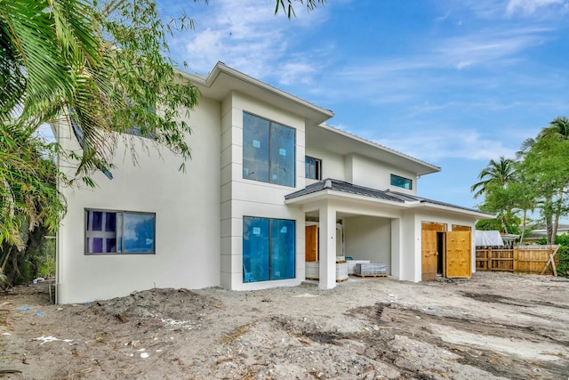 view of front of house featuring metal roof, stucco siding, and fence