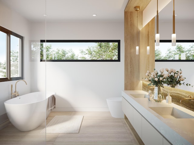 bathroom featuring toilet, a soaking tub, a sink, and a wealth of natural light