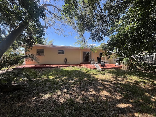 rear view of house with a patio, stucco siding, a yard, a deck, and fence