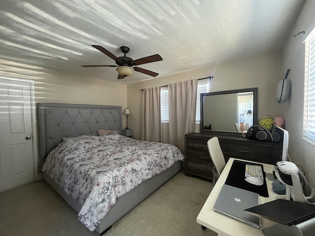 bedroom featuring light carpet, a textured ceiling, and a ceiling fan