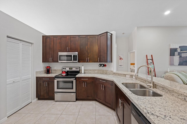 kitchen featuring dark brown cabinetry, recessed lighting, light tile patterned floors, appliances with stainless steel finishes, and a sink