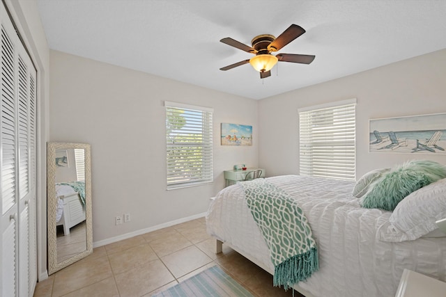 bedroom featuring light tile patterned flooring, baseboards, a ceiling fan, and multiple windows