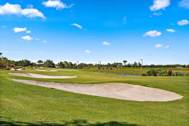 view of home's community with golf course view, a water view, and a lawn