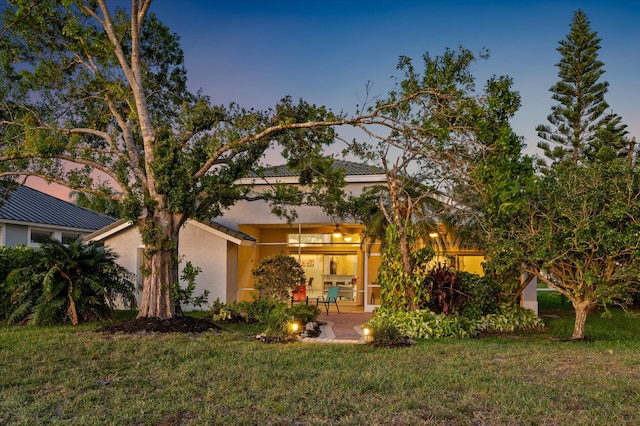 view of front of house with stucco siding, a front yard, and a patio area