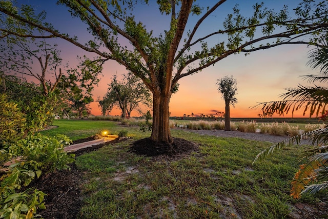 yard at dusk featuring a water view and an outdoor fire pit