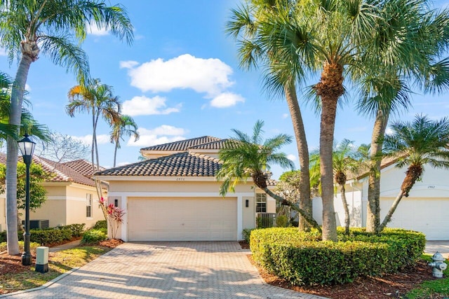 2476 NW 67th St, Boca Raton, FL 33496 - mediterranean / spanish-style house with a tiled roof, central AC, stucco siding, decorative driveway, and a garage