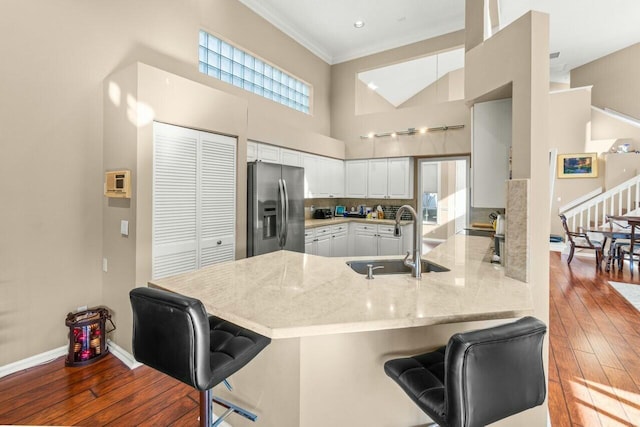 2476 NW 67th St, Boca Raton, FL 33496 - kitchen featuring a towering ceiling, stainless steel fridge, a peninsula, white cabinetry, and a sink