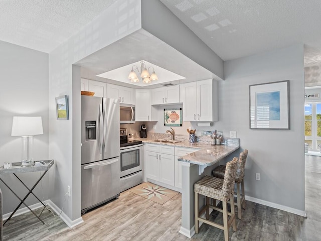 2800 Indian River Blvd Unit F8, Vero Beach, FL 32960 - kitchen featuring stainless steel appliances, a textured ceiling, white cabinets, a chandelier, and light stone counters