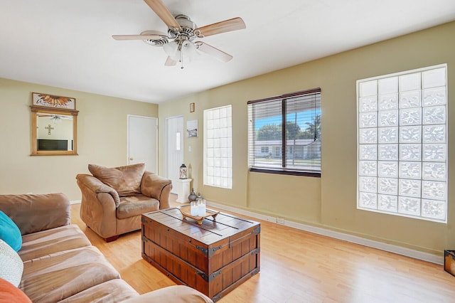living area featuring baseboards, a ceiling fan, and light wood-style flooring