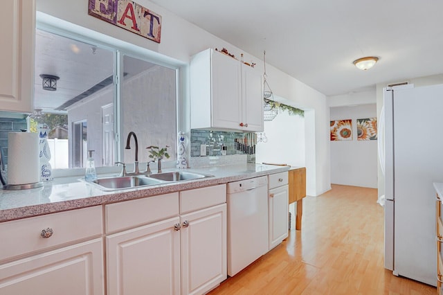 kitchen featuring tasteful backsplash, a sink, light countertops, white appliances, and light wood-style flooring