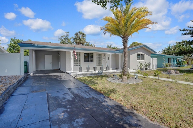 ranch-style house with fence, an attached carport, a porch, a front yard, and driveway