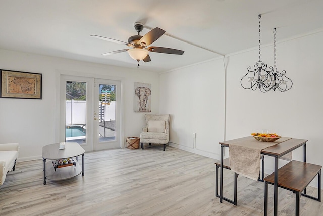 sitting room featuring baseboards, french doors, light wood finished floors, and ceiling fan with notable chandelier