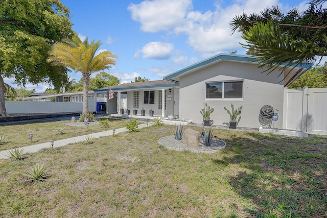 view of front of home featuring a front lawn, stucco siding, and fence