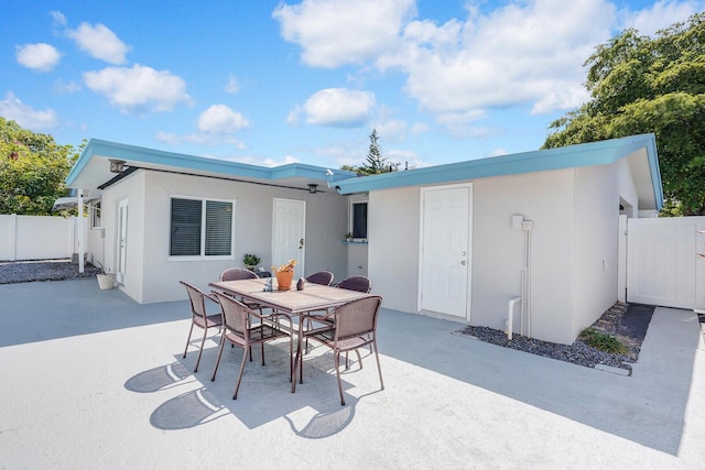 back of property with stucco siding, a patio area, fence, and outdoor dining space