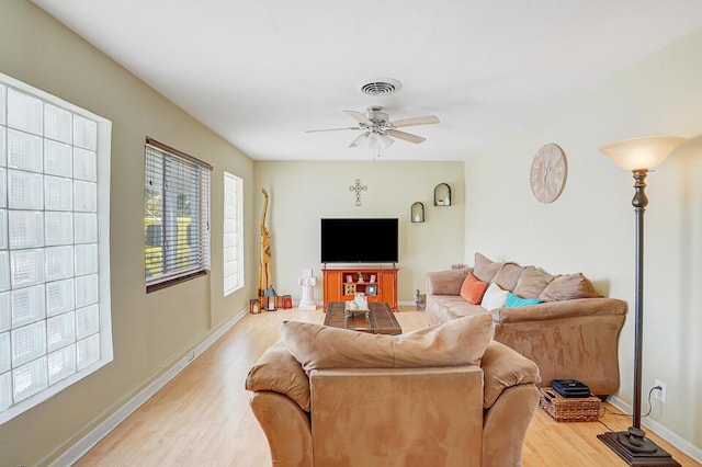 living room featuring a ceiling fan, baseboards, visible vents, and wood finished floors