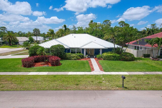 view of front facade featuring a standing seam roof, metal roof, and a front lawn