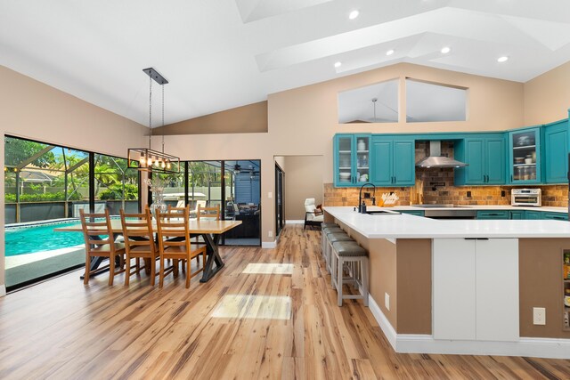 kitchen with wall chimney range hood, light wood-type flooring, and light countertops