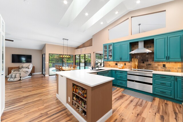 kitchen with black electric stovetop, wall chimney range hood, light wood-type flooring, light countertops, and a sink