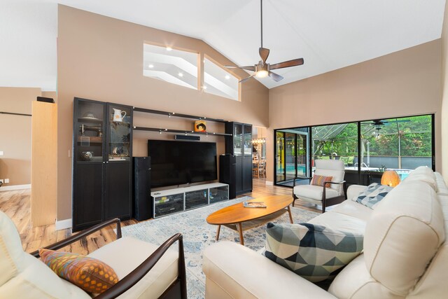 living room with a ceiling fan, a sunroom, wood finished floors, and high vaulted ceiling