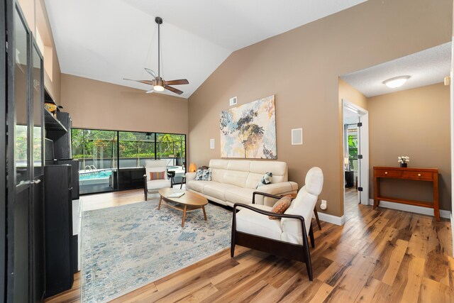 living room featuring light wood-style floors, ceiling fan, lofted ceiling, and a wealth of natural light